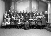 Skolklass fotograferad i ateljé med sin lärare, 1905.