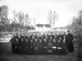 Klassfoto. Skolklass med fröken utomhus, med skolan i bakgrunden. Ca. 1900.