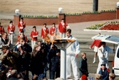 Bordtennisspelaren Jan-Ove Waldner tänder den olympiska elden som för första gången någonsin brinner i Göteborg. Detta i samband med travloppet Olympiatravet på Åbytravet i Åby, Mölndal, den 13 april 1996. I bakgrunden underhåller Mölndals Paradorkester.