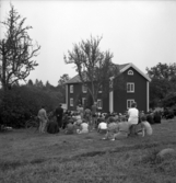 Skidfrämjandets dag. Fyllerydsstugan. Foto av en rödmålad mangårdsbyggnad. I förgrunden har samlats en hel del folk för att lyssna på invigningen av huset.