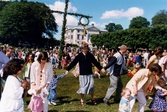 Midsommarfirande vid Gunnebo slott i Mölndal, den 20 juni 1997. Små och stora deltar i dansen kring midsommarstången.