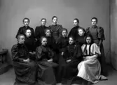 En grupp välklädda unga kvinnor fotograferade i ateljé. Ca. 1900.