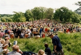 Midsommarfirande vid Gunnebo slott i Mölndal, den 20 juni 1997. Människor sitter i gröngräset och tittar på dansen kring midsommarstången.