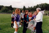 Kvarnbyvallen i Mölndal, år 1996. I samband med en fotbollsmatch mellan Jitex BK och Landvetter IF delas blombuketter ut till Jitex-spelarna Pernilla Bowall, Eva Larsson och Camilla Svensson. Matchen slutade 1-1.