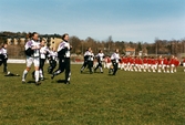 Kvarnbyvallen i Mölndal, år 1997. Fotbollslaget Jitex BK värmer upp inför en match mot Lotorps IF, vilken slutade med resultatet 0-1. Mölndals Paradorkester underhåller på fotbollsplanen.