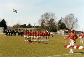 Kvarnbyvallen i Mölndal, år 1997. Fotbollslaget Jitex BK värmer upp inför en match mot Lotorps IF, vilken slutade med resultatet 0-1. Mölndals Paradorkester underhåller på fotbollsplanen.