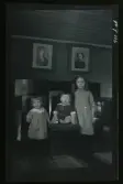 Tre barn porträtterade i ett hem. 
