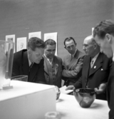 Glasets dag. Smålands Museum. Några herrar diskuterar något vid ett av borden i glasutställningen.