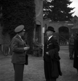 Försvarets dag. En officer med kamera, pratar med en äldre herre i kostym och medaljer m.m., vid vakten på I 11 i Växjö.