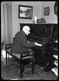 Utklädd person spelar piano. Fru Edna Ekstrand, Kolbäck.
Ur Gustaf Åhmans samling.