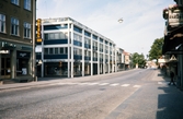 Storgatan, Växjö. Hörnet Storgatan/Bäckgatan med kvarteren Blenda och Stormen, med nytt affärshus.
Färgfoto, ca 1970.