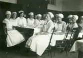 Elever i klass II grupp 1 vid Örebro läns småskollärarinneseminarium sittade vid dukade bord i skolköket, 1920-tal