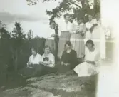 Elever vid Örebro läns småskollärarinneseminariums utflykt sitter på hällen och äter en kaka, 1922