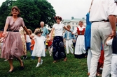 Midsommarfirande vid Gunnebo slott i Mölndal på 1990-talet. Små och stora deltar i dansen kring midsommarstången. Slottet i bakgrunden.