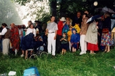 Midsommarfirande vid Gunnebo slott i Mölndal, okänt årtal. Vuxna och barn har tagit skydd undan regnet.