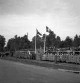 Kung Gustaf V:s besök i Liatorp 1939. Kungen talar från en tribun. Nedanför står  bl a en mängd lottor och lyssnar.