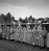 Kung Gustaf V:s besök i Liatorp 1939. 
Samling vid den kungliga tribunen. Man ser en mängd lottor och civila. 

Gustaf V (1858-1950), reg. 1907-1950.