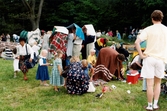 Midsommarfirande vid Gunnebo slott i Mölndal, okänt årtal. Vuxna och barn tar skydd undan regnet med vad som finns till hands.