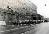 Högvakt, Stockholms slott,1972-03-19. 
Pågående vakt (med musikkår) ur I11 marscherar längs Lejonbacken, avgående vakt ur MP.
Mycket folk har samlats uppe på backen.