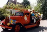 Studentexamen på Fässbergsgymnasiet i Mölndal den 5 juni 1997. En samling studenter får transport av en gammal brandbil. Fotografi taget på Frejagatan.