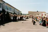 Studentexamen på Fässbergsgymnasiet i Mölndal den 5 juni 1997. Studenterna har kommit ut från skolbyggnaden och möts av familj och vänner på skolgården.