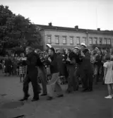 Studenterna, 1939.  Två studenter bärs iväg iväg utmed Stortorget. I bakgrunden syns Residenset.