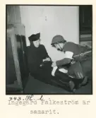 Luftskyddsövning vid Nordiska museet den 10 mars 1944. Ingegerd Falkeström är samarit, hon lägger ett förband om benet på en kvinna som sitter på golvet.
