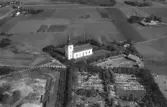 Exteriörbild. Flygbild över Stafsinge kyrka och kyrkogård med omliggande odlingslandskap.