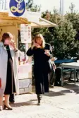 Lions Club anordnar marknad på Stadshusplatsen i Mölndal, tidigt 1980-tal. Två kvinnor äter korv med bröd och dricker Sunkist Apelsin till.