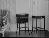 Två små runda bord varav ett draperat med tyg.
