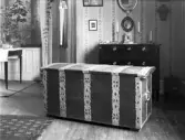 Interiör med kista med metallbeslag i förgrunden.

