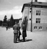 Kamratmötet, I 11. Tre herrar, varav en i uniform, pratar på kaserngården.
