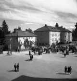 Kamratmötet, I 11. Vy över kaserngården, vid vakten (?). Mycket folk har samlats.