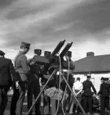 Kamratmötet, I 11. Demonstration av kulspruta på kaserngården. Några män i uniform m/23 demonstrerar.