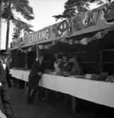 Kamratmötet, I 11. Servering vid övningsfältet. En man pratar med några lottor.