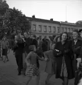 Studenterna 1940. 31/5 - 1/6. En manlig student bärs av sina kompisar längs Stortorget. I bakgrunden syns Residenset.