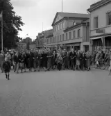 Studenterna 1940. 31/5 - 1/6. Studenter m.fl. på väg uppför Kungsgatan. I bakgrunden skymtar dåv. järnvägsstationen och kupolen till dåv. Växjö Högre Allmänna Läroverk.