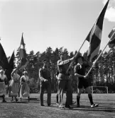 Medborgartåget, 16/6 1940. Fanborg på Värendsvallen. Två scouter och två män klädda i militäruniform går i täten, framför ett antal kvinnor, klädda i s.k. husmorsdräkt.