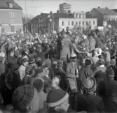 Studenterna andra dagen, 13/5 1958. 
Virrvarr av studenter och gratulanter på Stortorget. 
I bakgrunden syns några av husen längs Kronobergsgatan och byggnads-
ställningar runt domkyrkans torn.