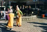 Påskfirande på Mölndals torg lördagen den 3 april 1999. Frälsningsarméns hornmusikkår spelar på den lilla scenen och tre påskkärringar dansar till musiken.