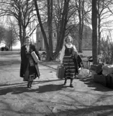 Avslutning vid Grimslövs folkhögskola.
Några unga kvinnor i folkdräkt (Värendsdräkt och till höger Rättviksdräkt) lämnar 
folkhögskolan, bärande på några väskor.
