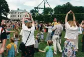 Midsommarfirande vid Gunnebo slott i Mölndal, år 1999. Dans kring midsommarstången för små och stora. Slottet i bakgrunden.