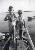 Stig och Siv på bryggan en sommardag med båt i bakgrunden, 1930-tal.