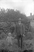 Man och barn i trädgård, 1920-tal