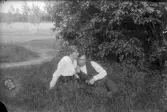 Man och kvinna vilar i skuggan av en buske, 1920-tal