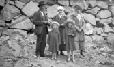 Familj poserar framför mur, 1920-tal