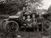 Hallands tredje bil, en T-Ford. Chaufför Per Persson, Attorp, Ljungby. Personerna bakom bilen: Längst bak, Selma Persson. Fr v Julius Johansson, Selma Johansson, Elsa Johansson, Alma Johansson, Karl Berntsson och Ester Berntsson. På trampbrädan, fr v, Harry Johansson, Rosa Persson, Anna Johansson och John Johansson.