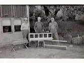 Tillverkning av värpreden och foderbord för höns. Personerna på bilden fr v Bertil Heimroth, Axel Johansson och Tufve Johansson. Flickan i bakgrunden heter Laila Åkerberg. Fototid ca 1950.