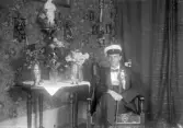 Man i studentmössa och studentkäpp vid blosteruppvaktning i hemmet, 1920-tal