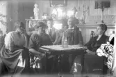 Grupp samlade runt bord i hemmet, 1920-tal